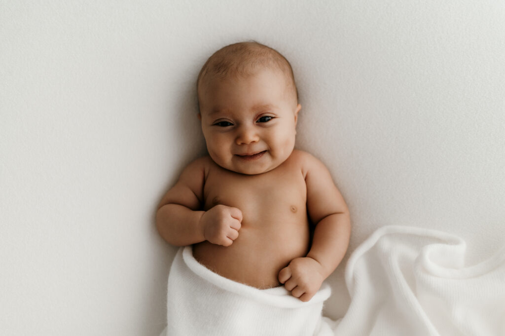 Newborn resting on textured knit blanket in natural light