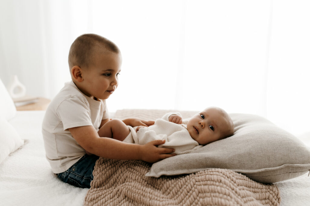 Big brother interaction with newborn in natural light lifestyle photo