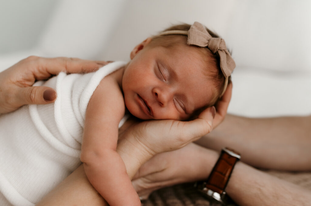 Baby girl held by mom and dad in natural light