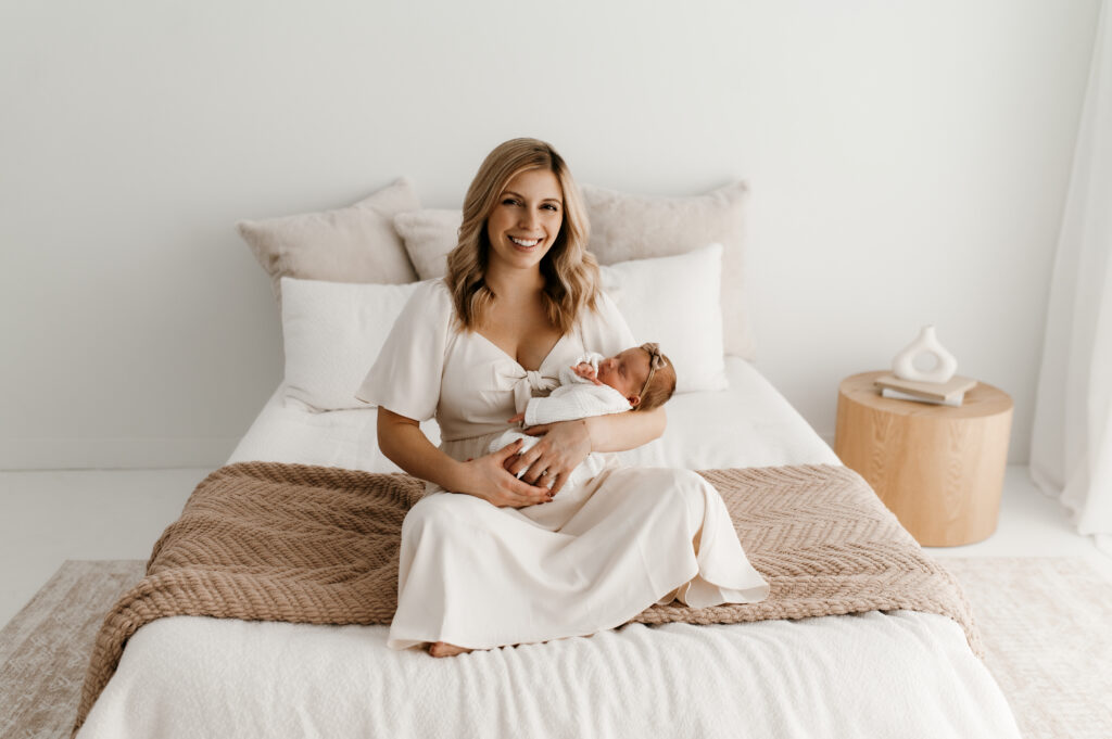 Mom holding newborn in neutral cream outfit during in-home lifestyle newborn session