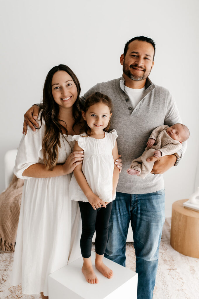 sister leaning into parents holding newborn baby
