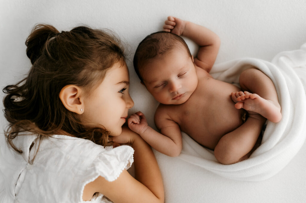 candid moment of siblings interacting with newborn baby