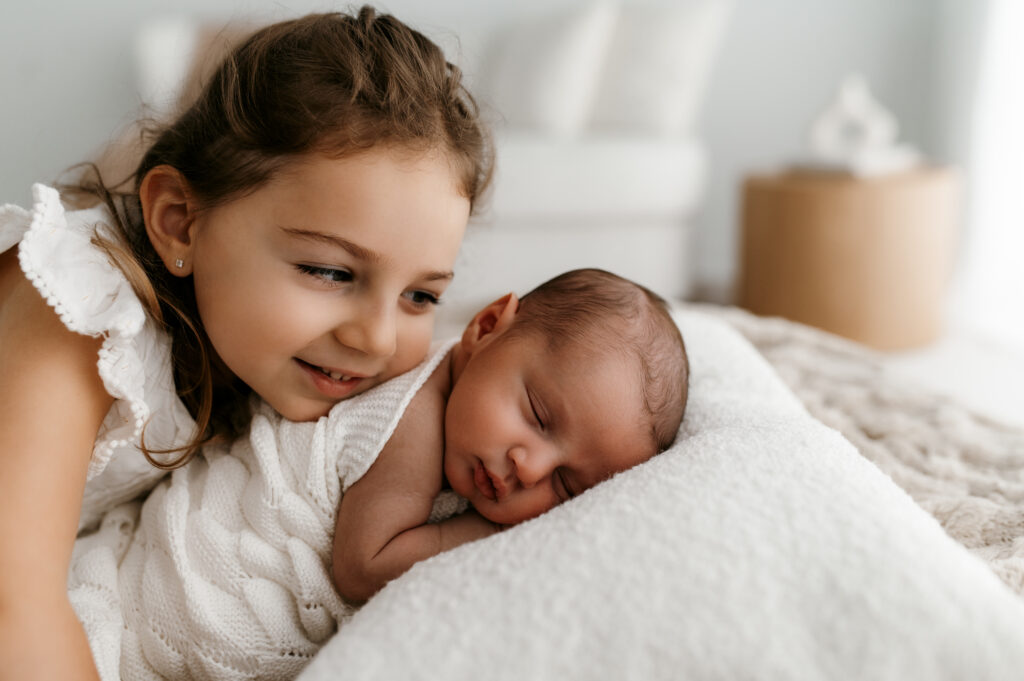 candid moment of siblings interacting with newborn baby