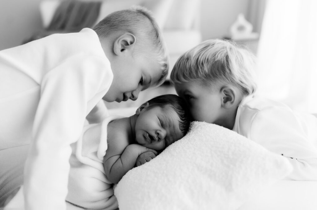 siblings bonding with newborn baby during relaxed studio session 