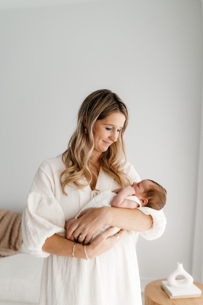 Mom holding newborn in natural light newborn portraits 