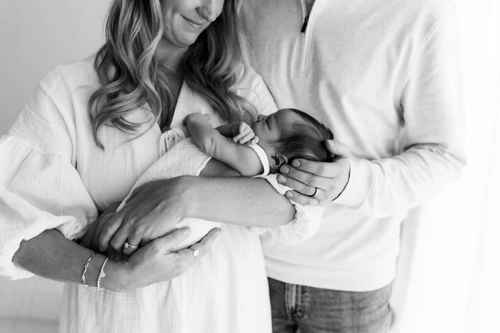 Mom and dad embracing infant against shoulder in peaceful setting
