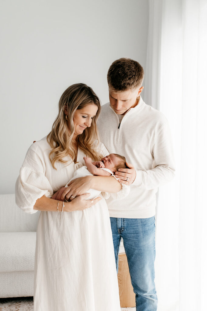 Mom and Dad adoring their newborn in soft natural light