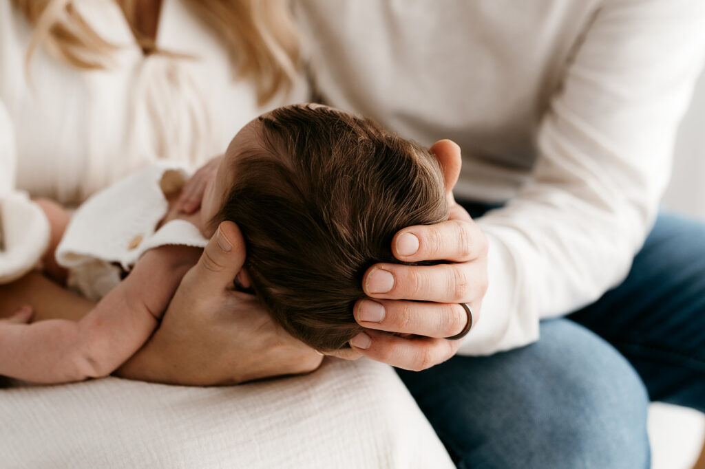 Parents cradling baby in arms during relaxed newborn session