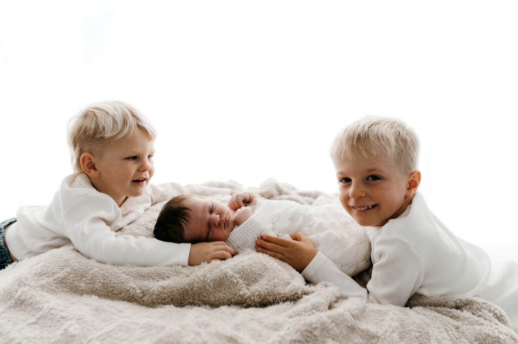 siblings bonding with newborn baby during relaxed