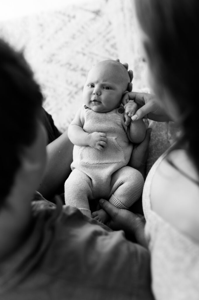 New parents holding their newborn during a relaxed studio photo session