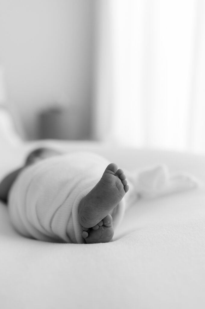 Close up of newborn baby feet resting on a soft neutral blanket