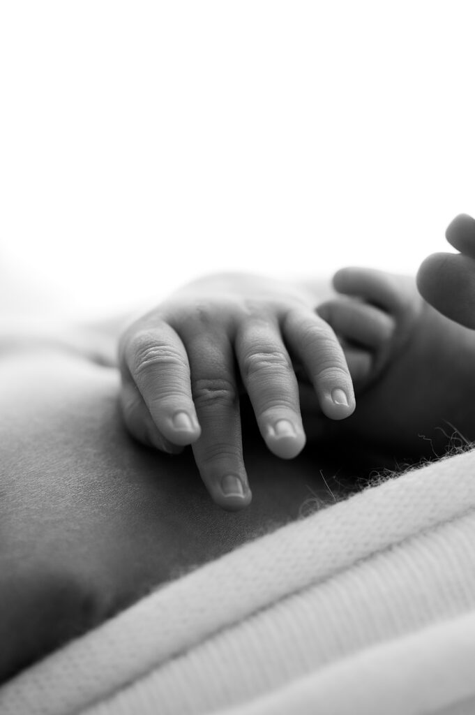 Tiny baby fingers and toes touching in peaceful newborn pose