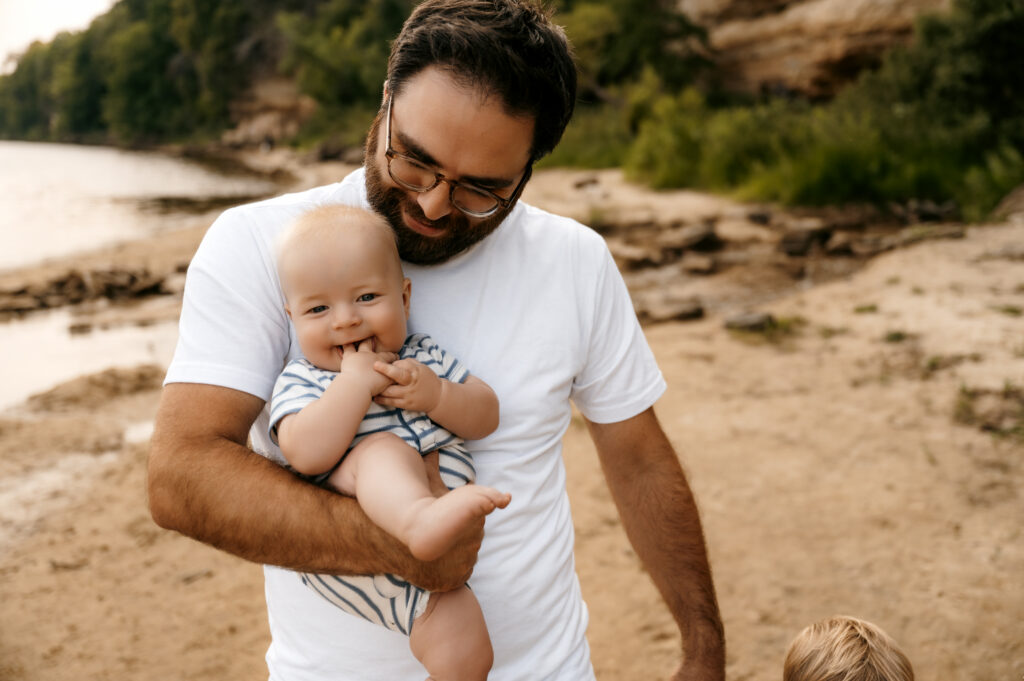 Dad and baby smiling together at a family beach session
