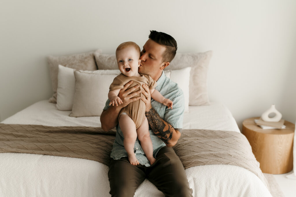 Dad kissing baby at a studio photo session with nature light